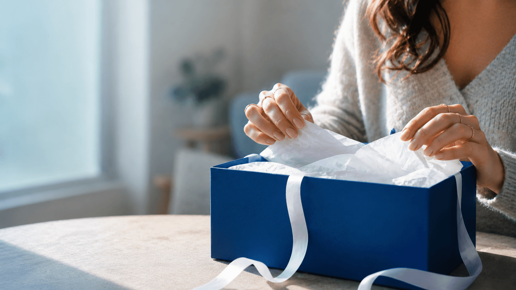 Vrouw pakt een cadeau uit terwijl ze ontdekt wat erin zit, origineel cadeau voor je vriendin